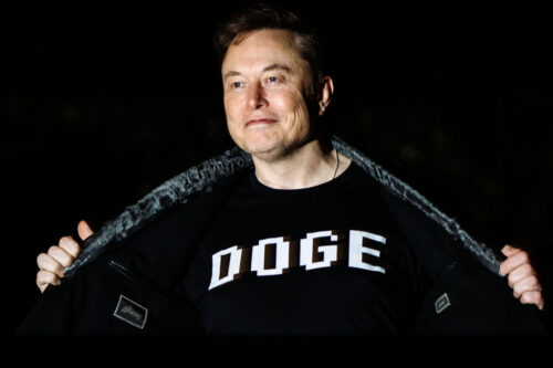 Elon Musk walks to the White House after landing in Marine One showing off his DOGE shirt.