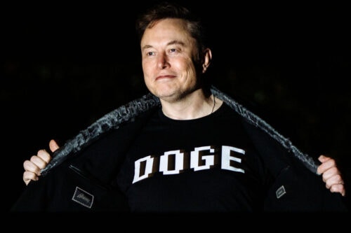 Elon Musk walks to the White House after landing in Marine One showing off his DOGE shirt.
