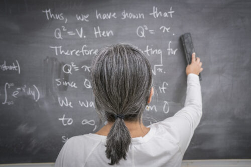 Woman erasing blackboard in classroom