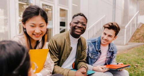 Four students sitting outside of their school