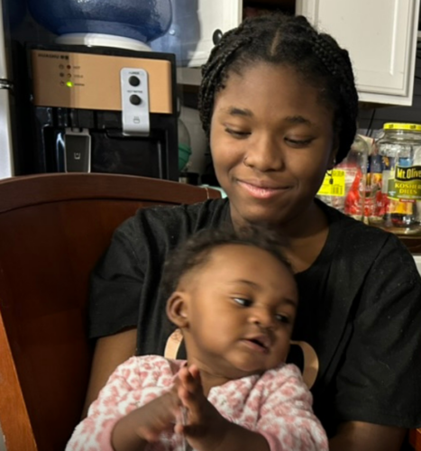 Woman holding her young baby sitting on a couch.