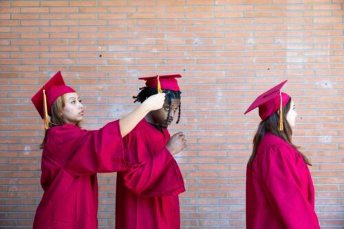 three young students in graduation regalia
