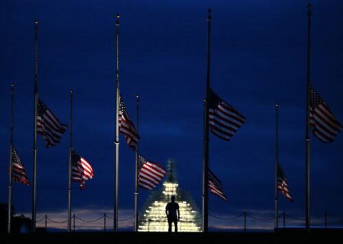 A man walks past a row of American flags that have been lowered to half staff on the Washington Monument grounds, near the US Capitol on September 11, 2015 in Washington, DC.