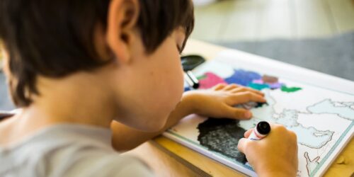 Mixed race boy coloring map with crayon