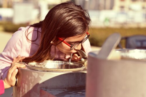 Child drinking from water fountain.
