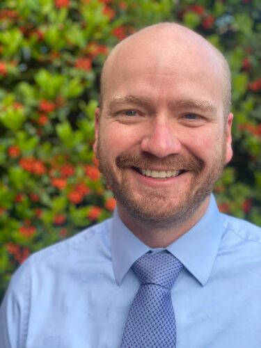 Rob Trombley smiling wearing a blue tie.