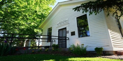 White wooden building labeled as the birthplace of the Republican Party, surrounded by green foliage.