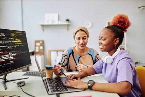 Woman teaches student at a computer.