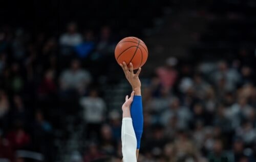 two hands reach for basketball in the air