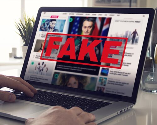 A close shot of a laptop with a news website pulled up, large red letters spell out 