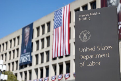 US DOL building sign with building and America flag in background
