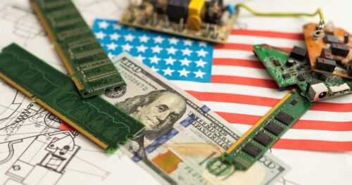 American flag laid under a $100 bill, and circuit boards
