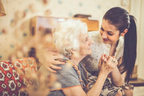 Granddaughter embracing her happy grandmother at home