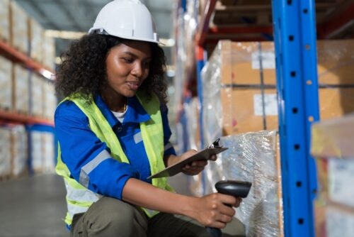 A young Black apprentice works in a large warehouse