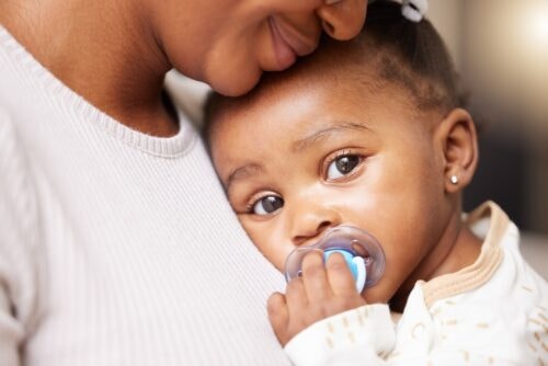 women holding infant with pacifer.