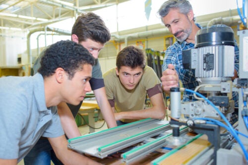 Man operating a machine in front of his apprentices