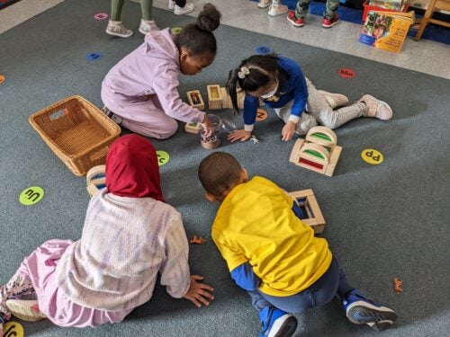 Children playing on the floor with various colorful toys.