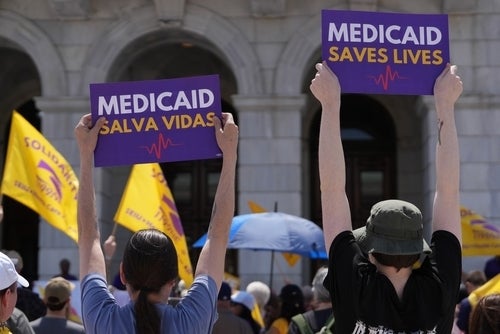 Protestors hold up signs that say 