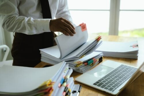 Black man with a tie looks through stack of papers