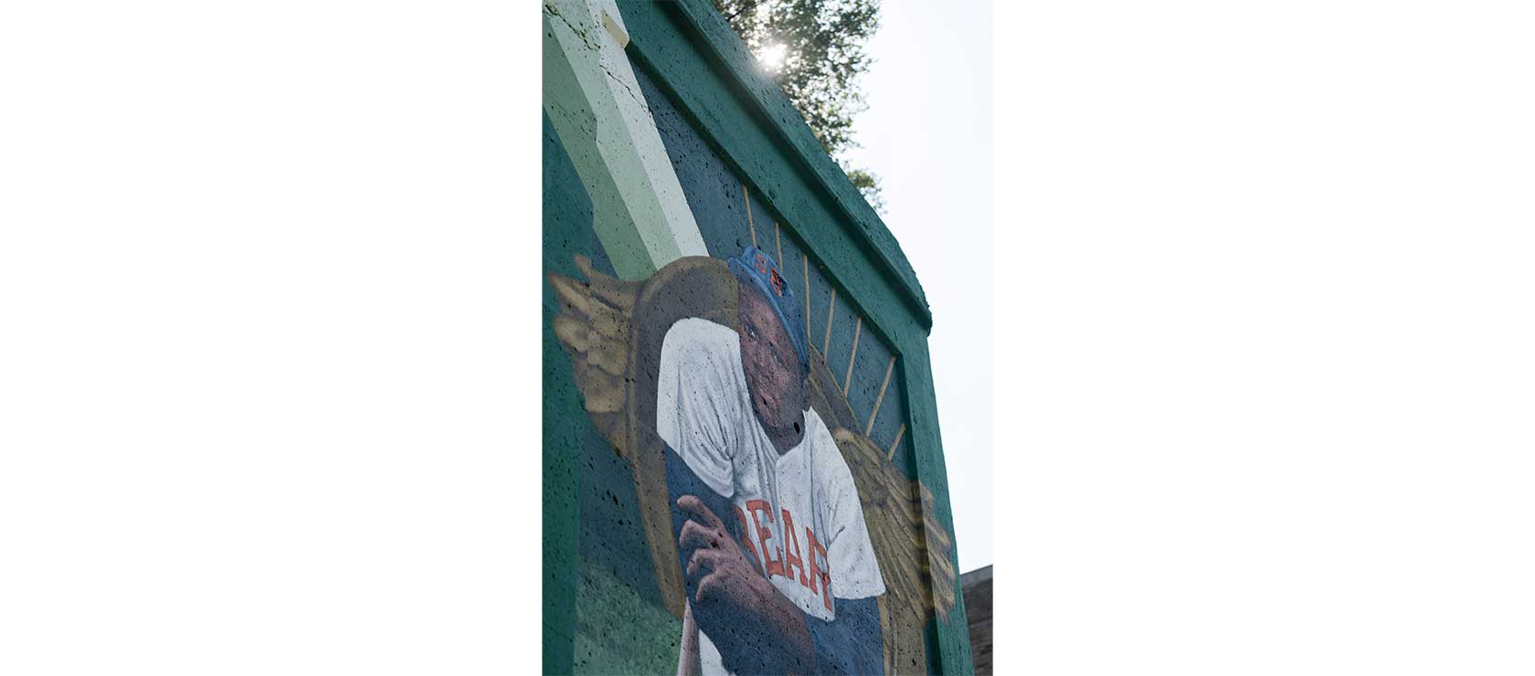 A mural of a seated baseball player wearing a white uniform with 