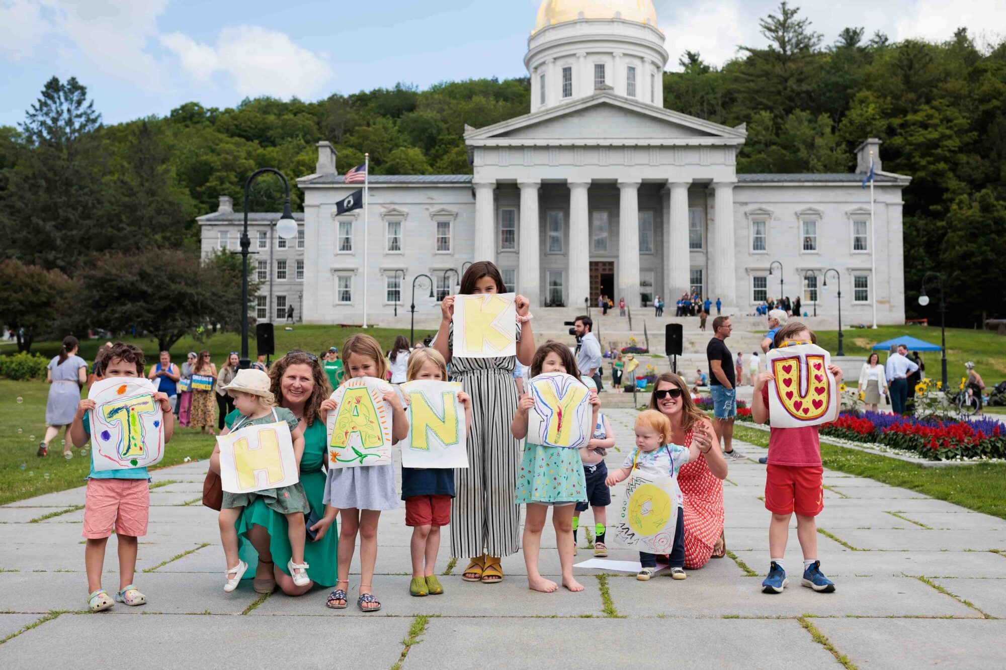 Children and adults holding signs spelling 