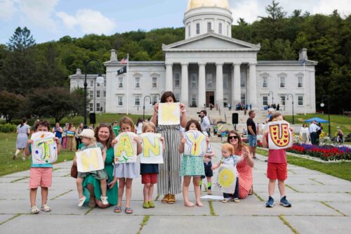 Children and adults holding signs spelling 