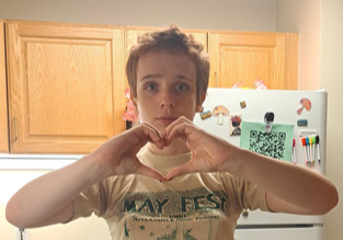 A white adolescent shows the heart sign with his hands