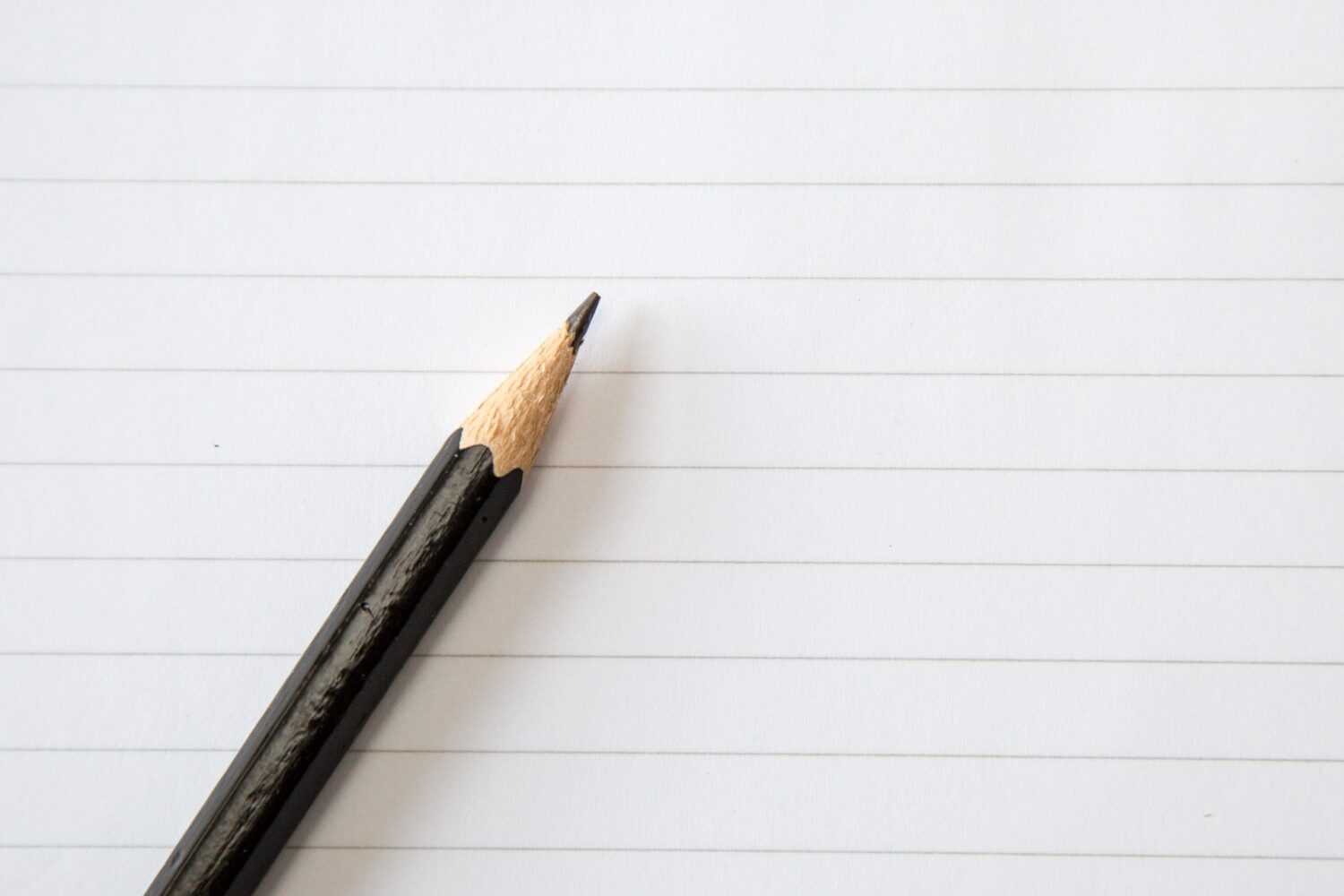 Half of a brown pencil is visible on top of blank lined paper.