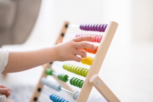 child's hands play with colored abacus