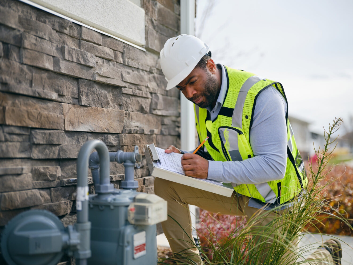 Technician Examining and Adjusting a Home Natural Gas Meter on the exterior of a residential home.