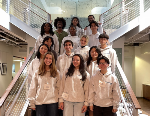 14 interns on a staircase smiling for a photo.