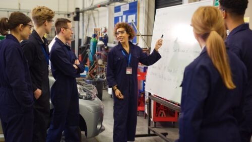 Instructor discusses automotive training with students in a hands-on workshop.