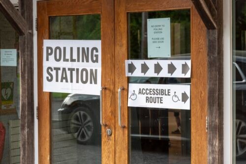 Wooden double doors with signs denoting a polling station and directions to an accessible route.