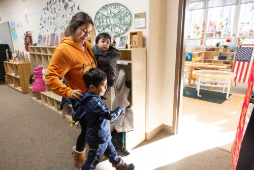 Mother dropping a young boy in the early morning at a child care center on a college campus.
