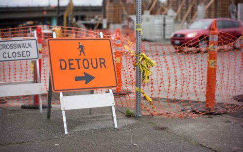 Picture of a roadblock with a detour and road closed sign.