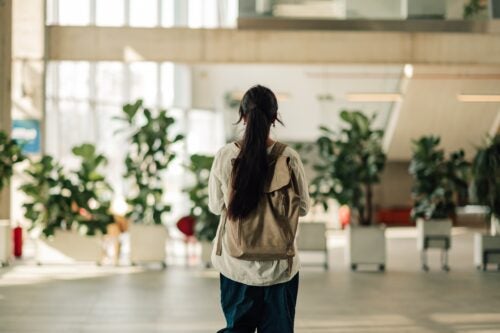 a student wearing a backpack walks in an all white lobby