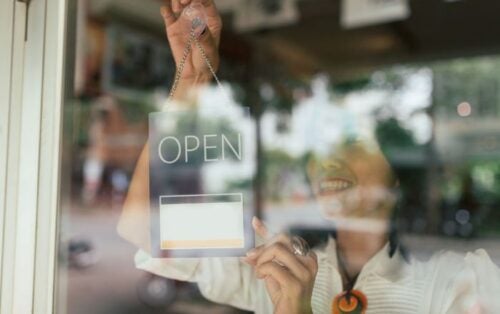 Woman hangs open sign on business door