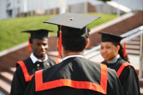 Three graduates in caps and gowns talking to each other