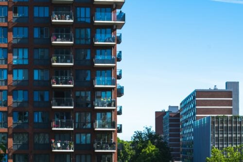 Tall apartment complex with balconies in right half of image foreground, with other multifamily buildings in the background.
