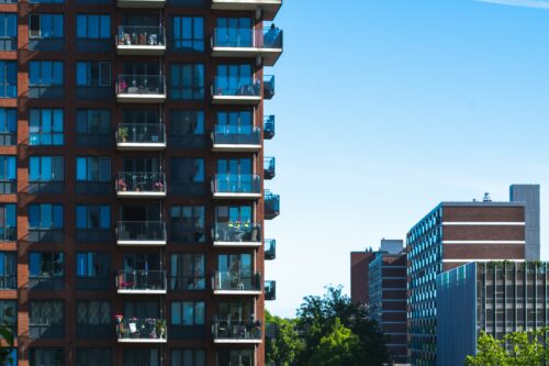 Tall apartment complex with balconies in right half of image foreground, with other multifamily buildings in the background.